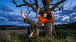 © Matos - Joyful Woman Swinging on Tire Swing Under Moonlit Evening Sky