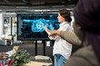 © DC Studio - Startup entrepreneur presents machine learning technology to investors on a screen, explaining company innovations and competitive advantages during a business pitch for an AI venture.