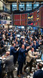 © Mirivox - Crowded stock trading floor with men in suits, focusing on screens displaying market data, symbolizing fast-paced finance and business activity.