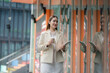 © Thitiporn - Happy workday concept. Smiling businesswoman walks with coffee and tablet in a modern office district. businesswoman, workday, coffee, professional, career, corporate lifestyle