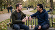 © nasrudin - Two male friends sitting on park bench having deep conversation for mental health and social connection