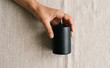 © SimpleDesignStudio - A person holding a black pillar candle on a neutral fabric background for home decor and aromatherapy