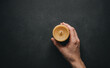 © SimpleDesignStudio - A person holding a yellow beeswax candle on a dark background viewed from above representing cozy mood and relaxation