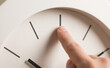 © SimpleDesignStudio - Finger touching a minimalist clock face representing time management and punctuality