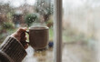 © SimpleDesignStudio - Cozy rainy day warm coffee cup by the window in autumn, comfortable lifestyle concept