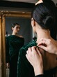 © Creative man - Close-up behind-the-scenes photograph of a professional fashion model being styled by a fashion professional, only hands of the stylist visible adjusting an elegant premium garment