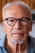 © simona - Senior man with white hair and beard wearing black round glasses, looking directly at the viewer with a thoughtful expression, representing aging and wisdom