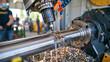 © Maksym Tereshchenko - Close-up of industrial CNC equipment machining a large steel cylinder, cutting tool removing material and producing metallic chips, coolant spraying across the workpiece, highly detailed machine int