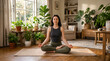 © Vilanouth - Young woman meditating in lotus position on a yoga mat in a cozy sunlit room with indoor plants