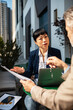© Davor - Business professionals discussing documents at outdoor city cafe
