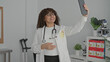 © Krakenimages.com - Woman doctor wearing stethoscope holding tablet up for video call in clinic building; telemedicine reassurance.