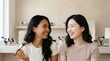 © SITI - Two cheerful Asian women smiling and holding makeup brush while doing beauty routine at vanity table