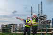 © BESTIMAGE - Engineers team inspecting petroleum engineering in oil refinery inspection check collaboration at fuel industrial plant Two Male engineers hold laptop pointing away and talk radio at site evening