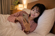 © Susie - スマホに夢中で夜更かしする日本人の若い女性