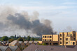 © MarshallChan - Thick Black Smoke Rising Over Residential Area on Clear Day with Modern Buildings