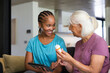 © WavebreakMediaMicro - Adult woman sitting on living room sofa holding tablet while senior woman holding pill bottle