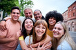 © CarlosBarquero - Mobile selfie of group young multi-ethnic beautiful friends having fun together outdoors. Excited people looking at happy camera enjoying sightseeing in city on sunny day. Generation z and vacations.