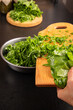 © Inna Nikitina - Chef hands cooking fresh green sorrel leaves close up. Putting chopped organic spinach or herbs into metal bowl. Vertical rustic kitchen food photography with human interaction