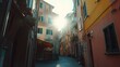 © Rahmat - Sunlight rays shine down a narrow street between tall colorful houses in a historic Mediterranean village during a summer evening as tourists walk along the cobblestone paths near the seaside