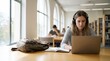 © GunGun - Young university student studying with a laptop and notebook in a bright contemporary library, focused natural expression, digital education concept, soft daylight, shallow depth of field, copy space