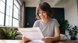 © Eve - Smiling young woman reviewing financial statement document at home wooden desk, managing family budget planning, analyzing investment income report, tax return, and accounting stability.