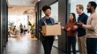 © Eve - Smiling Black businesswoman carrying cardboard box in office while multiethnic colleagues applaud, representing career promotion, job hiring, onboarding welcome, and team work appreciation.