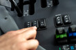 © Marina - Driver pressing speed control switch on dashboard panel inside modern agricultural tractor cabin, adjusting cruise control and machinery settings during field work.