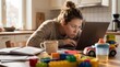 © pithak - Stressed mother working on laptop at messy kitchen table surrounded by children toys photography