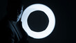 © Premium_art - Silhouette of a man holding a glowing circular light in a dark setting.