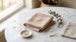 © zalfa_std98 - Folded linen napkins and eucalyptus branch on a white marble table by a window.