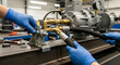 © BLHDNG - Hands in blue protective gloves working on intricate industrial equipment, connecting hoses and fittings to a motor and pump system in a workshop.