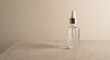 © Chari - Clear glass dropper bottle with serum on beige stone surface