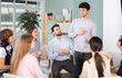 © JackF - Active young guy standing and talking to interested students sitting in a circle indoors