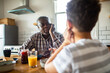 © Marko Geber - Senior man talking with child at kitchen table