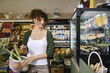 © Aleksei Isachenko/imageBROKER - Woman leading healthy lifestyle bought fresh fruits and vegetables in grocery store but looks with interest at cakes and desserts on display. She resists temptation to break her diet