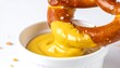 © Ana - A fresh soft pretzel being dipped into a bowl of yellow mustard.