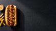 © Rasel - Toasted hot dog bun with frankfurter and condiments near golden fries on slate background for fast food promotion.