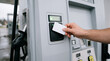 © Santiphab - Close up of hand holding a credit card to pay for gasoline at a modern fuel dispenser machine. Contactless gas station payment technology.