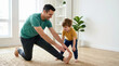 © OlgaNeuroArt - Father and son doing morning stretches on the living room floor. Dad teaching his child flexibility exercises at home. Active family lifestyle and indoor fitness concept
