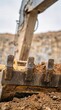 © pufanya - Vertical close up of worn steel teeth on excavator bucket. Scratched heavy machinery with rust brown soil. Industrial mining equipment detail