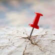 © Hayyat - Red pushpin marking location on cracked concrete surface with blurred background