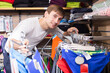 © caftor - Young man shopping for swimwear in clothing store