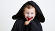 © Alexander - Close-up portrait of a young vampire wrapped in a black cape, pale face and theatrical blood makeup around the mouth, sinister playful stare, Halloween vampire, gothic child, spook