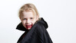 © Alexander - Close-up portrait of a young vampire wrapped in a black cape, pale face and theatrical blood makeup around the mouth, sinister playful stare, Halloween vampire, gothic child, spook