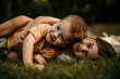 © La Famiglia - Children embracing on grass, expressing happiness and sibling love