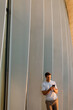 © BGStock72 - Relaxed moment of a young man using his phone by a sleek architectural wall