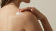 © Christos - Woman applying moisturizing body cream to shoulder during summer skincare routine at home