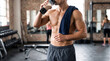 © Hussain - Shirtless muscular man drinking protein shake after intense gym workout session