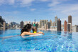 © leungchopan - Mother holding toddler boy in rooftop pool overlooking hong kong city