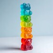 © Debasish - Colorful gummy bear candies stacked in a tall rainbow tower on a soft light blue background, with bright studio lighting and a playful sweet treat theme.